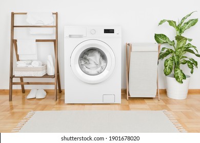 Waschküche mit moderner Waschmaschine und Textilien