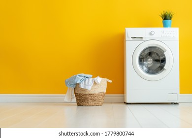 Interior Of Laundry Room With A Washing Machine On Bright Yellow Wall Background.