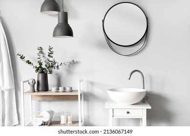 Interior of light bathroom with small table, sink and shelving unit