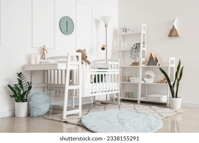Interior of light bedroom with baby crib, changing table and shelving unit - Shutterstock ID 2338155291