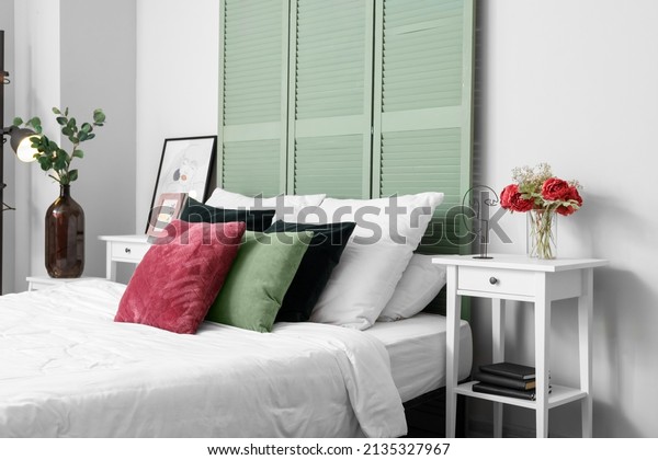 Interior of light bedroom with green folding\
screen and tables