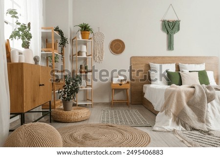 Interior of light bedroom with shelf units, commode and plants