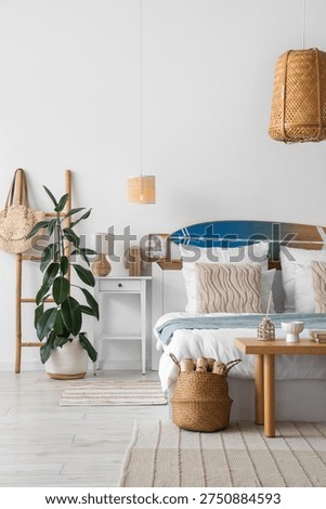 Interior of light bedroom with surfboard, table and ladder