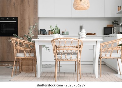 Interior of light dining room with table and wicker chairs