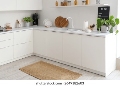 Interior of light kitchen with counters and wicker carpet
