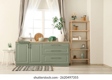 Interior of light kitchen with green counters, window, sink and shelving unit