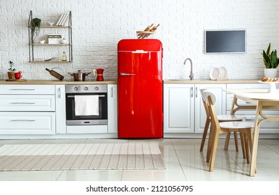 Interior de cocina ligera con frigorífico rojo, mostrador blanco y mesa de comedor