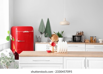 Interior of light kitchen with red fridge and counters