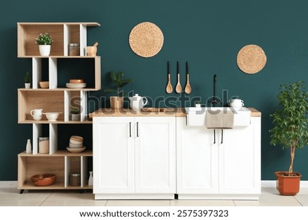 Interior of light kitchen with shelving unit and white counters near blue wall