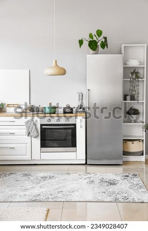 Interior of light kitchen with stylish fridge, counters and shelving unit