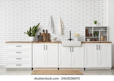 Interior of light kitchen with white counters, houseplant and utensils - Powered by Shutterstock