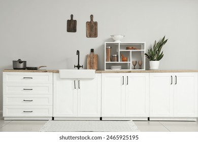 Interior of light kitchen with white counters, houseplant and utensils - Powered by Shutterstock