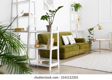 Interior of light living room with book shelves, green sofa and houseplants - Shutterstock ID 2141112355