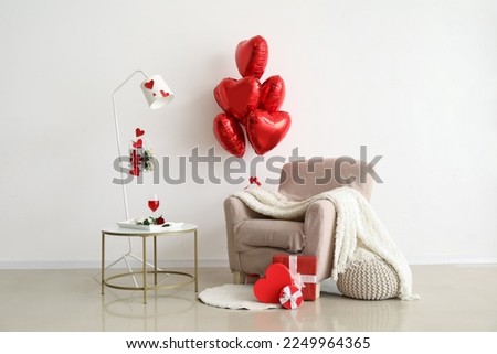 interior of light living room decorated for Valentine's Day with balloons, armchair and table