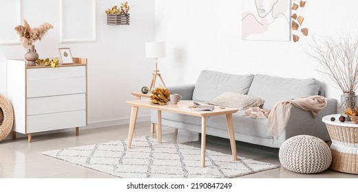 Interior Of Light Living Room With Grey Sofa, Table And Autumn Decor