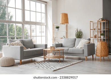 Interior of light living room with grey sofas, coffee table and large window - Shutterstock ID 2338829017