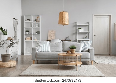 Interior of light living room with grey sofa, coffee table and shelf units - Powered by Shutterstock