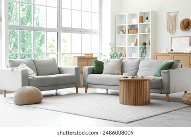 Interior of light living room with grey sofas, shelf unit and plants - Powered by Shutterstock