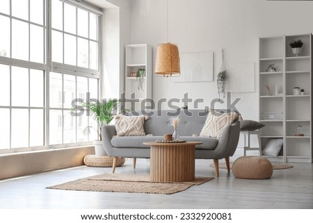 Interior of light living room with grey sofa, wooden coffee table and big window 商業照片 © 