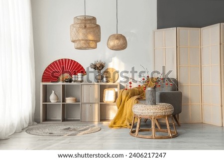 Interior of light living room with grey armchair and traditional Chinese decorations. Chinese New Year celebration