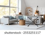 Interior of light living room with sofas, table and musical instruments