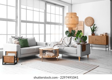 Interior of light living room with sofas and Monstera houseplant