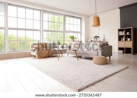 Interior of light living room with sofas and modern gadgets on table