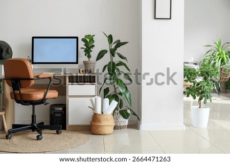 Interior of light office with comfortable workspace, modern computer and houseplants