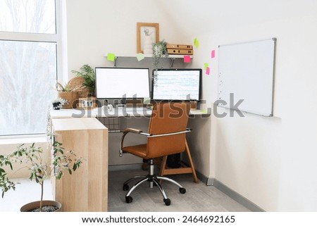 Interior of light office with programmer's desk, whiteboard and sticky notes
