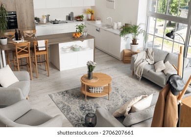 Interior of light open plan kitchen with coffee table, armchairs and sofas