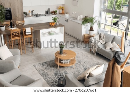 Interior of light open plan kitchen with coffee table, armchairs and sofas