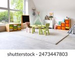 Interior of light playroom with toys, teepee and chalkboard in kindergarten