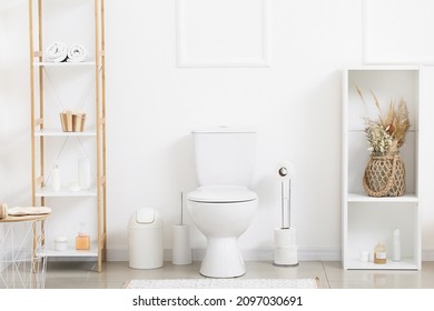 Interior of light restroom with toilet bowl, paper holder and shelf units - Shutterstock ID 2097030691