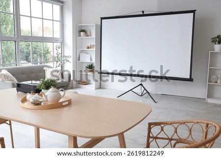 Interior of light room with projector screen and dining table