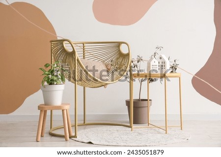 Interior of living room with armchair, cushion and coffee table with decoration near spotty wall