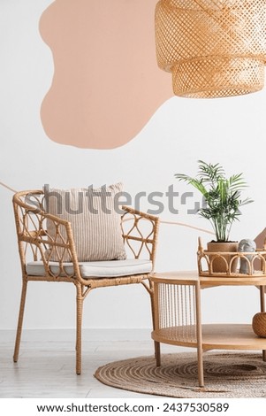 Interior of living room with armchair, cushion and coffee table near spotty wall