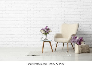 Interior del salón con sillón, mesa y flores lilas en jarrones