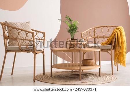 Interior of living room with armchairs, cushion and plaid near spotty wall