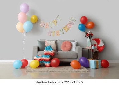Interior of living room decorated for birthday with balloons, pinatas and garland