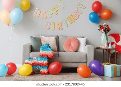Interior of living room decorated for birthday with balloons, pinatas and garland