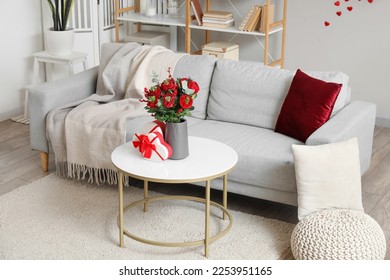 Interior of living room decorated for Valentine's Day with sofa, flowers and gifts
