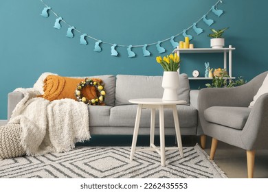 Interior of living room with Easter wreath, paper rabbits and sofa