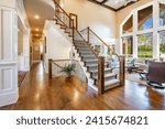 Interior living room with fireplace stone and wood mantle staircase wooden flooring decorated and staged large bright windows classic and modern decor