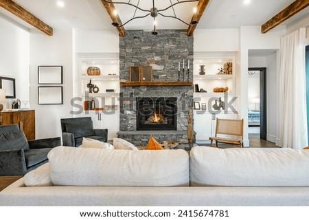 Interior living room with fireplace stone and wood mantle staircase wooden flooring decorated and staged large bright windows classic and modern decor
