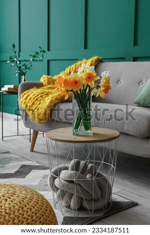 Interior of living room with grey sofa and narcissus flowers on coffee table