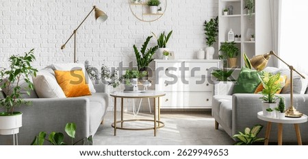 Interior of living room with grey sofas, tables and houseplants