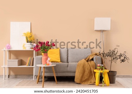 Interior of living room with sofa, Easter decor and flowers