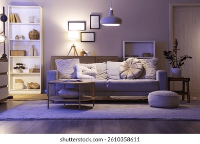 Interior de la sala de estar con sofá, estante y lámparas brillantes en la noche