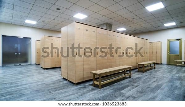 Interior of a locker room. Clean empty\
dressing room with big lockers and wooden\
bench
