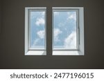 Interior low angle view at closed white Tilt Window Skylights at attic and background of sunny blue sky.